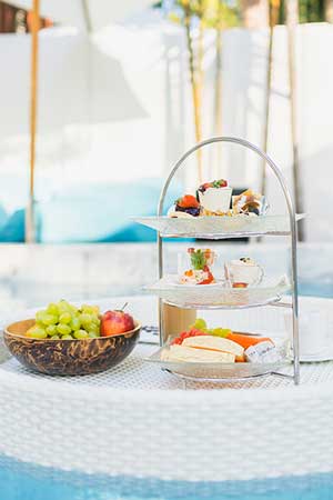 bowl of fruit and desserts floating on raft in swimming pool.