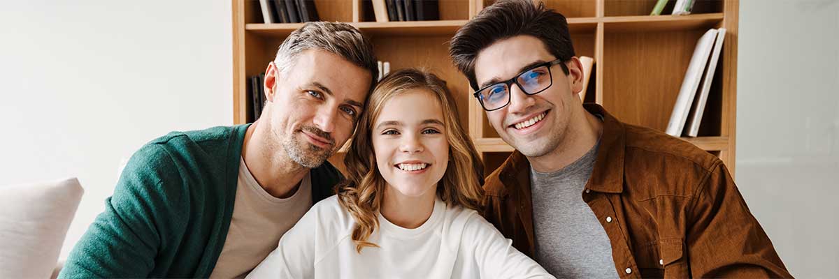gay male couple with teen girl sitting on couch.