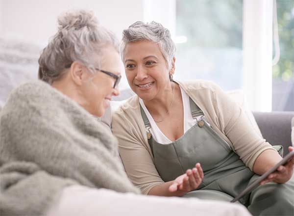 oldeer lesbian couple on sofa looking at iPad.