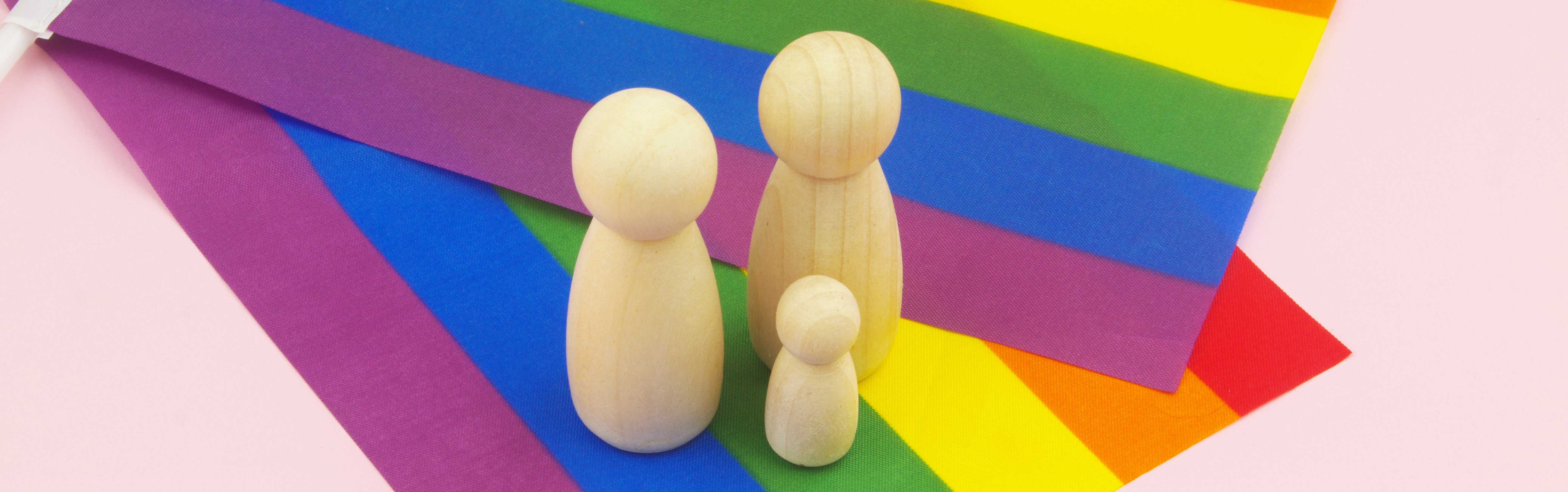 rainbow flags on table with wooden family icons.
