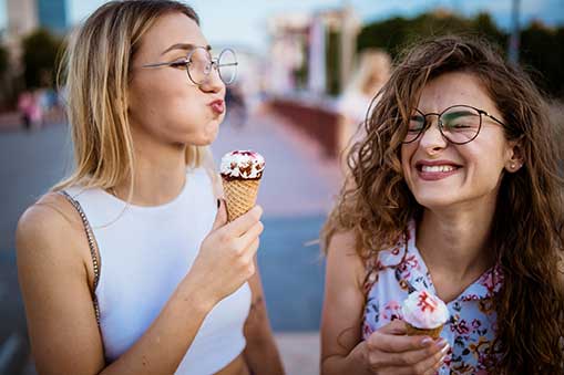 two women being funny eating ice cream cones.