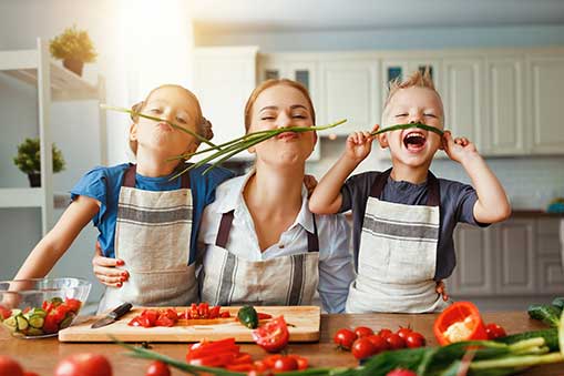 mother and 2 kids in kitchen with green bean mustaches.