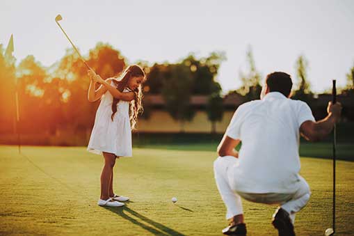 little girl golfing with man.